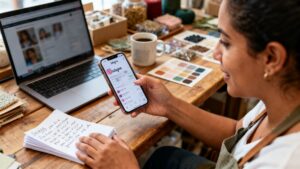Fotografía documental realista de una emprendedora colombiana en su tienda o estudio revisando en su teléfono las estadísticas de seguidores e interacción de la cuenta de Instagram de su negocio; pantalla con datos genéricos desenfocados, luz natural y entorno de trabajo auténtico, sin gráficos falsos ni estética de banco de imágenes.